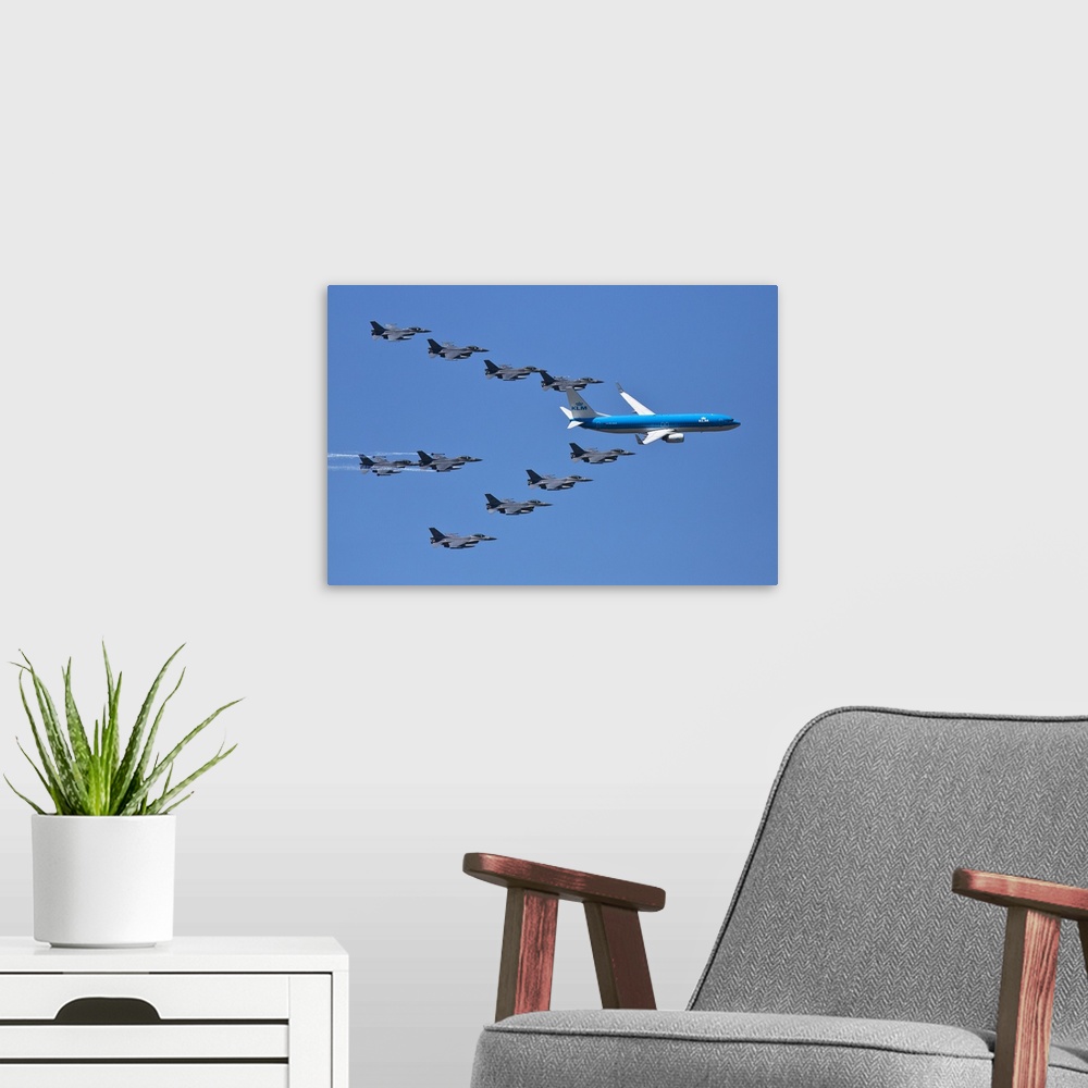 A modern room featuring A fleet of grey jets fly in formation around a blue commercial airliner.