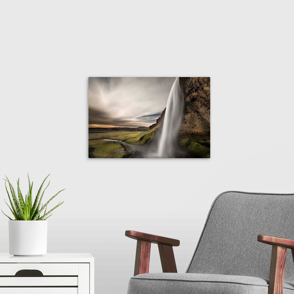 A modern room featuring Waterfall on the side of a cliff in a lush valley in Iceland.