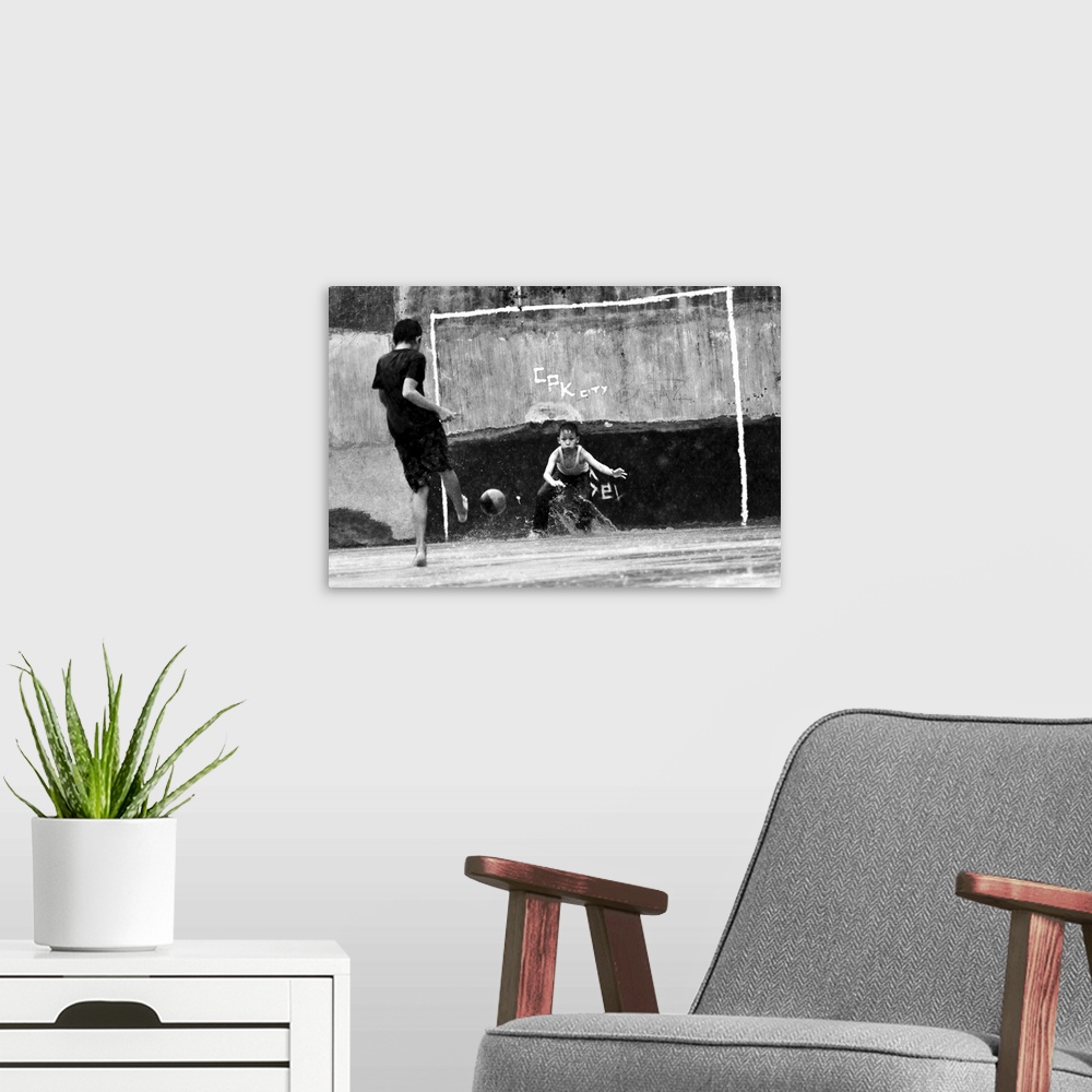 A modern room featuring Two boys kick a soccer ball near a makeshift goal.