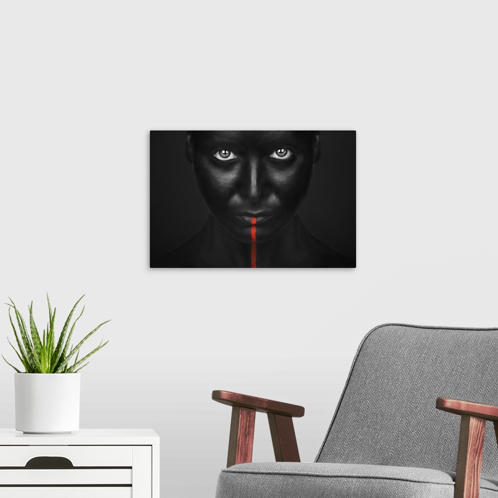 A modern room featuring A person with completely black bodypaint covering their face with a single red stripe running dow...