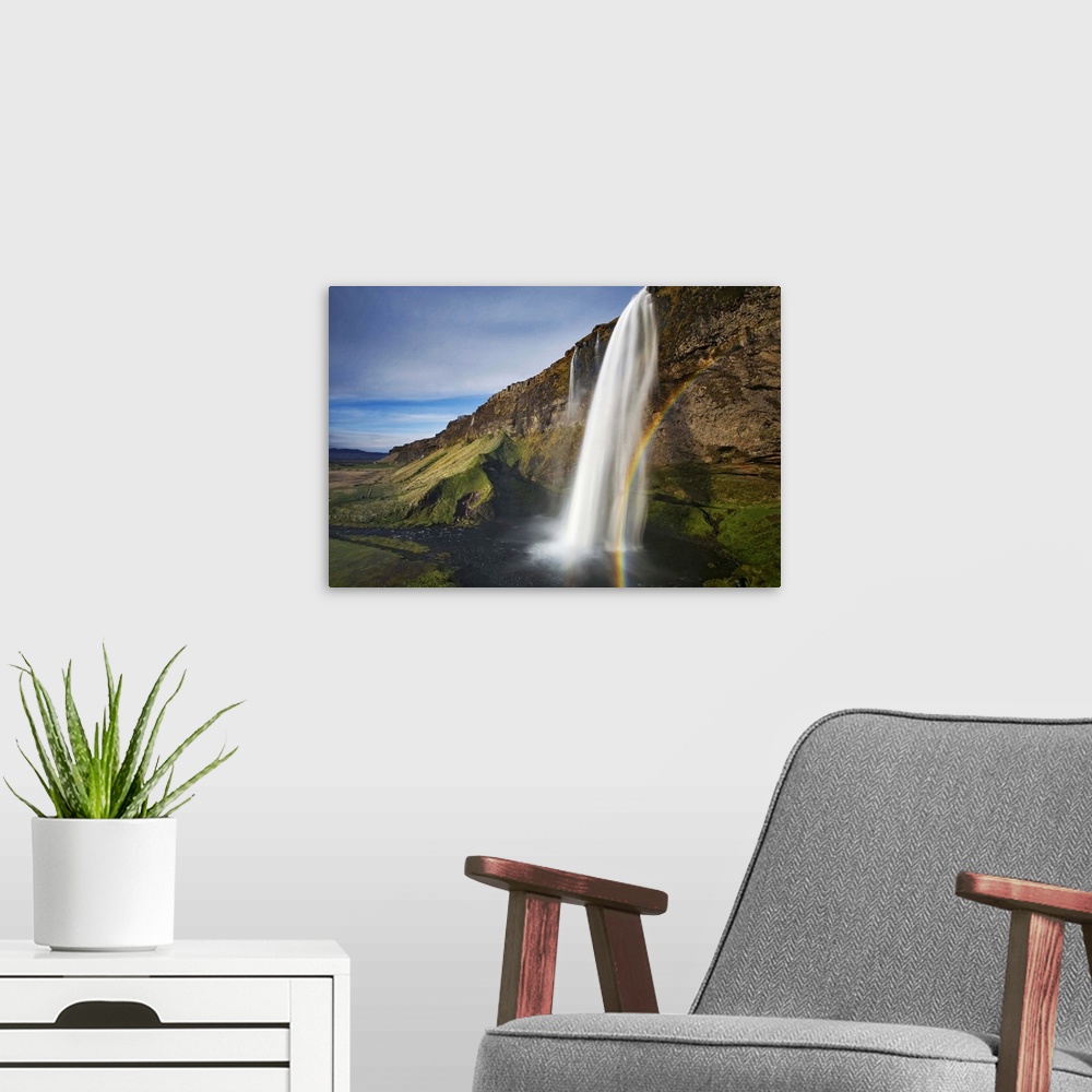 A modern room featuring A waterfall in a cliff with a rainbow, Seljalandsfoss, Iceland.