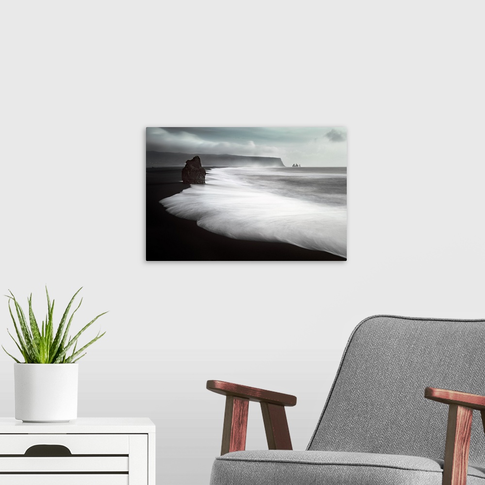A modern room featuring Sea stacks on a black sand beach with rushing water on the coast of Iceland.