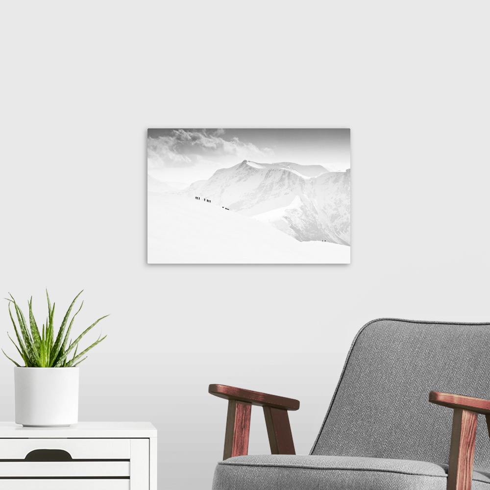 A modern room featuring Small figures walking up a completely snow-covered mountain with snowy peaks in the distance, Vei...