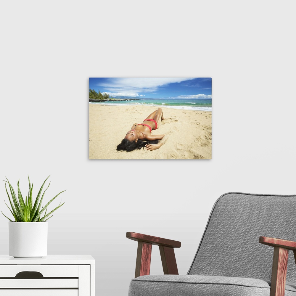 A modern room featuring A Young Woman In A Red Bikini Lays On A Sandy Beach; Maui, Hawaii, United States Of America