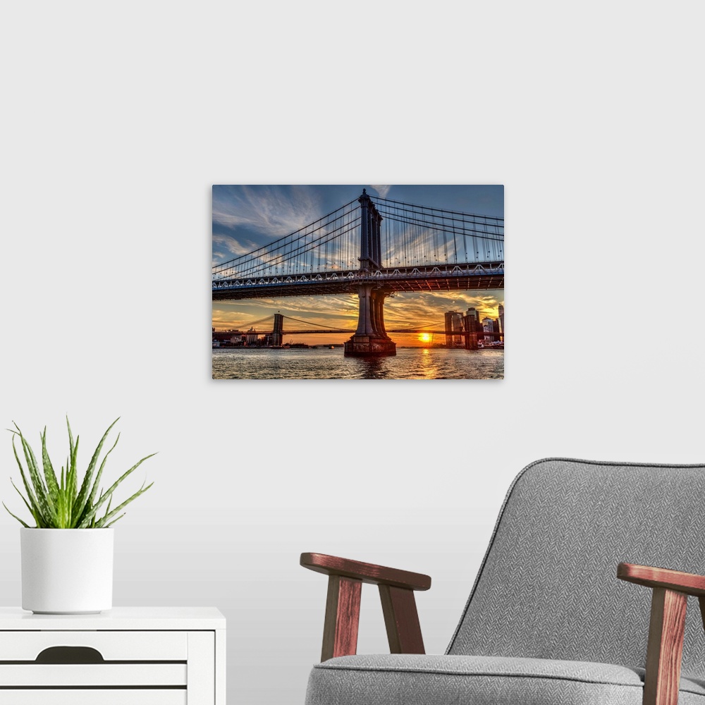 A modern room featuring Sun setting behind Manhattan and Brooklyn Bridges; New York City, New York, United States of America