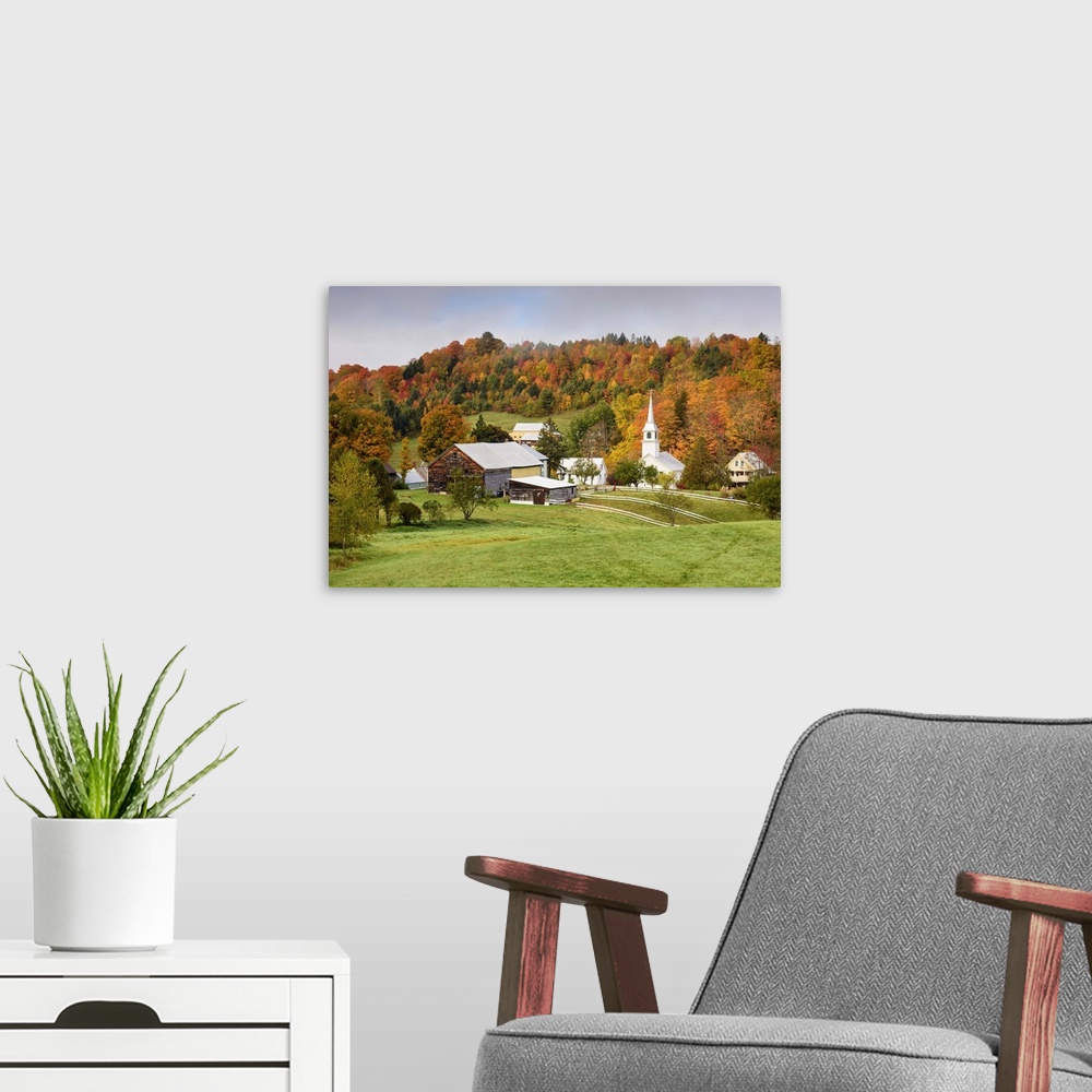 A modern room featuring Landscape photograph of a hilly village with Fall trees and fog.