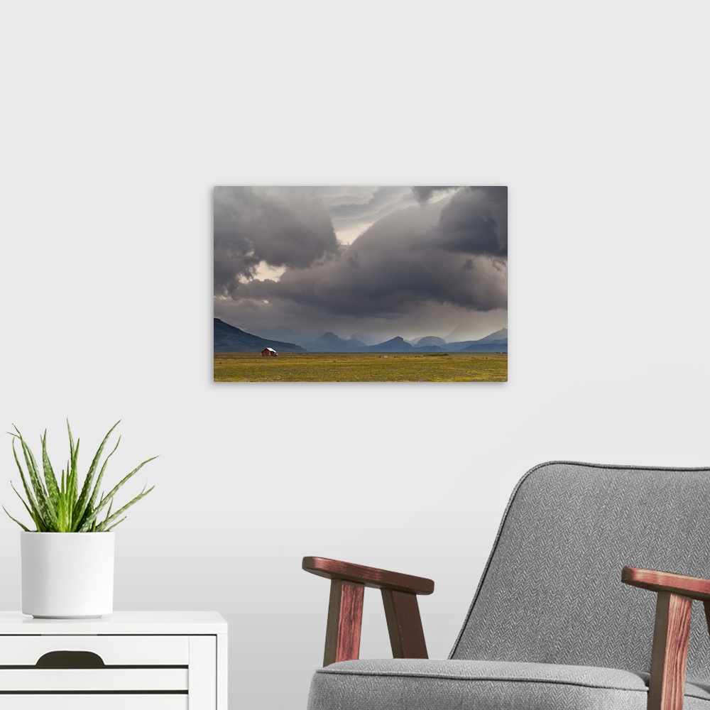 A modern room featuring A photograph of a dramatic cloudscape hanging over an Icelandic landscape.
