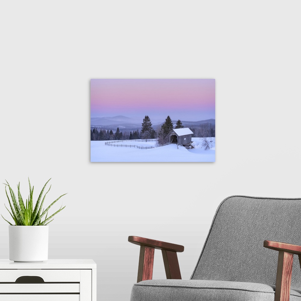 A modern room featuring Landscape photograph of a rural Winter scene with fog covered mountains in the background and a b...