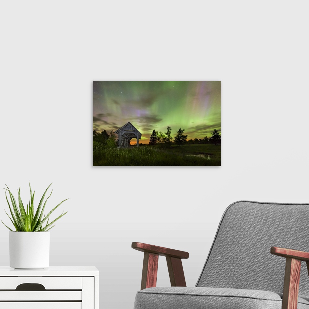 A modern room featuring Long exposure photograph of the Northern Lights at night in an open field with a covered bridge.