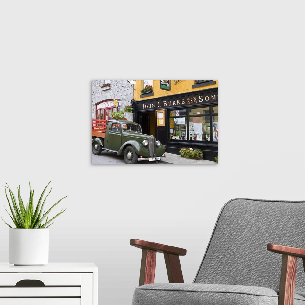 A modern room featuring Clonbur, Ireland. An old truck sits outside John Burke's, a well-known restaurant.