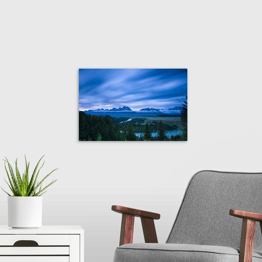 A modern room featuring Clouds illuminated with red light above the Grand Teton mountains seen from the Snake River looko...