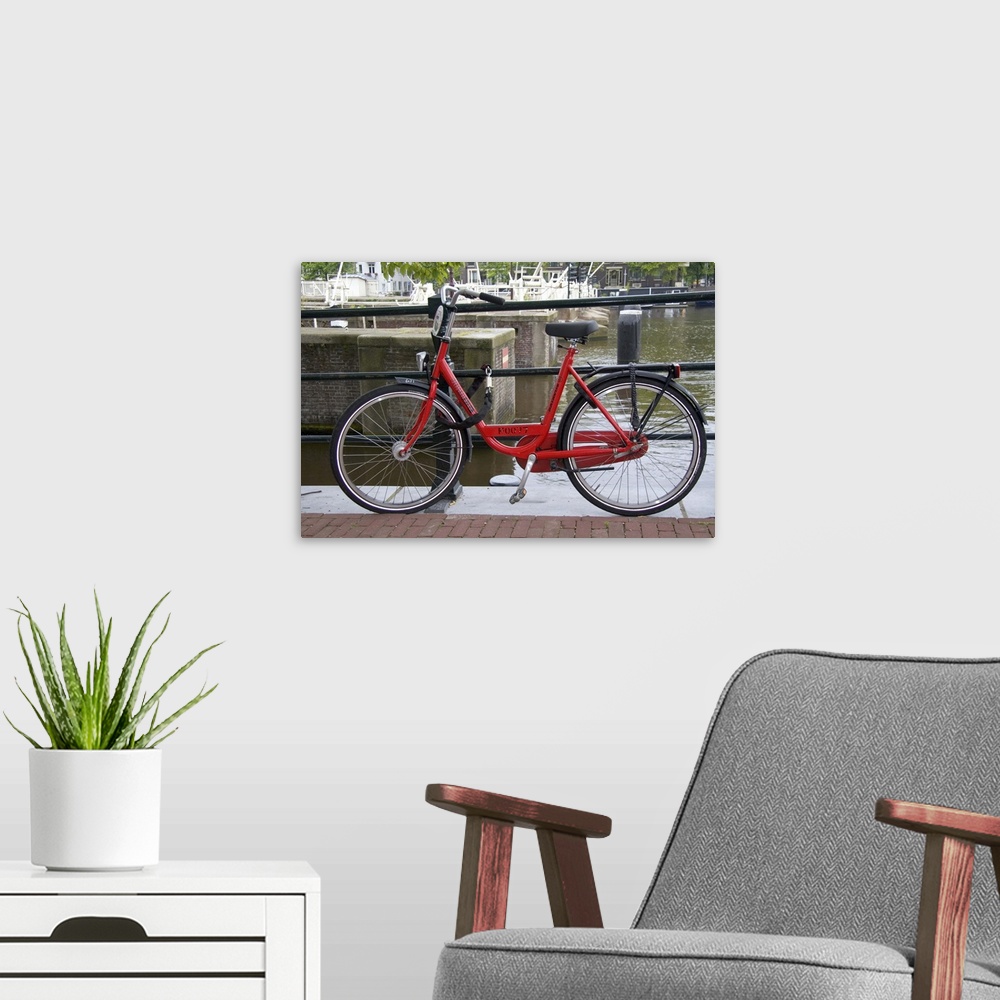 A modern room featuring Rental bicycle parked along the Amstel River in Amsterdam, Netherlands.