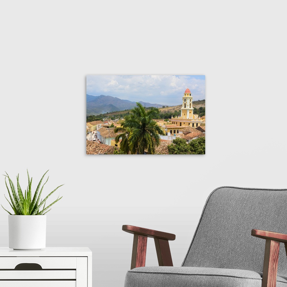 A modern room featuring Trinidad Cuba from above tower with church and mountains with buildings of tile roofs of second o...