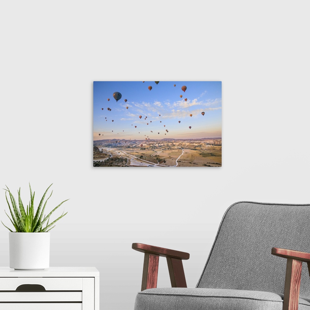 A modern room featuring Turkey,Anatolia,Cappadocia, Goreme. Hot air balloons flying above/among rock formations and field...