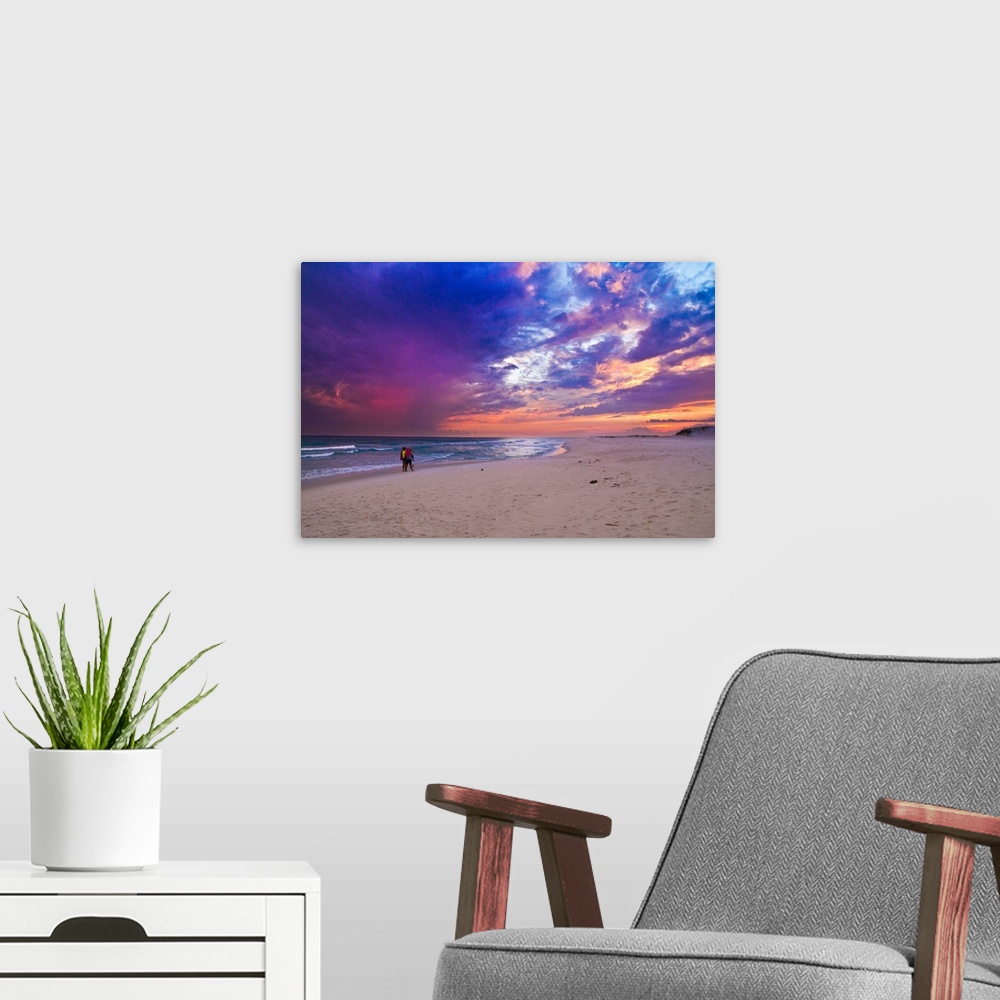 A modern room featuring People walking on the beach during a pink and purple sunset along the Gulf Islands National Seash...