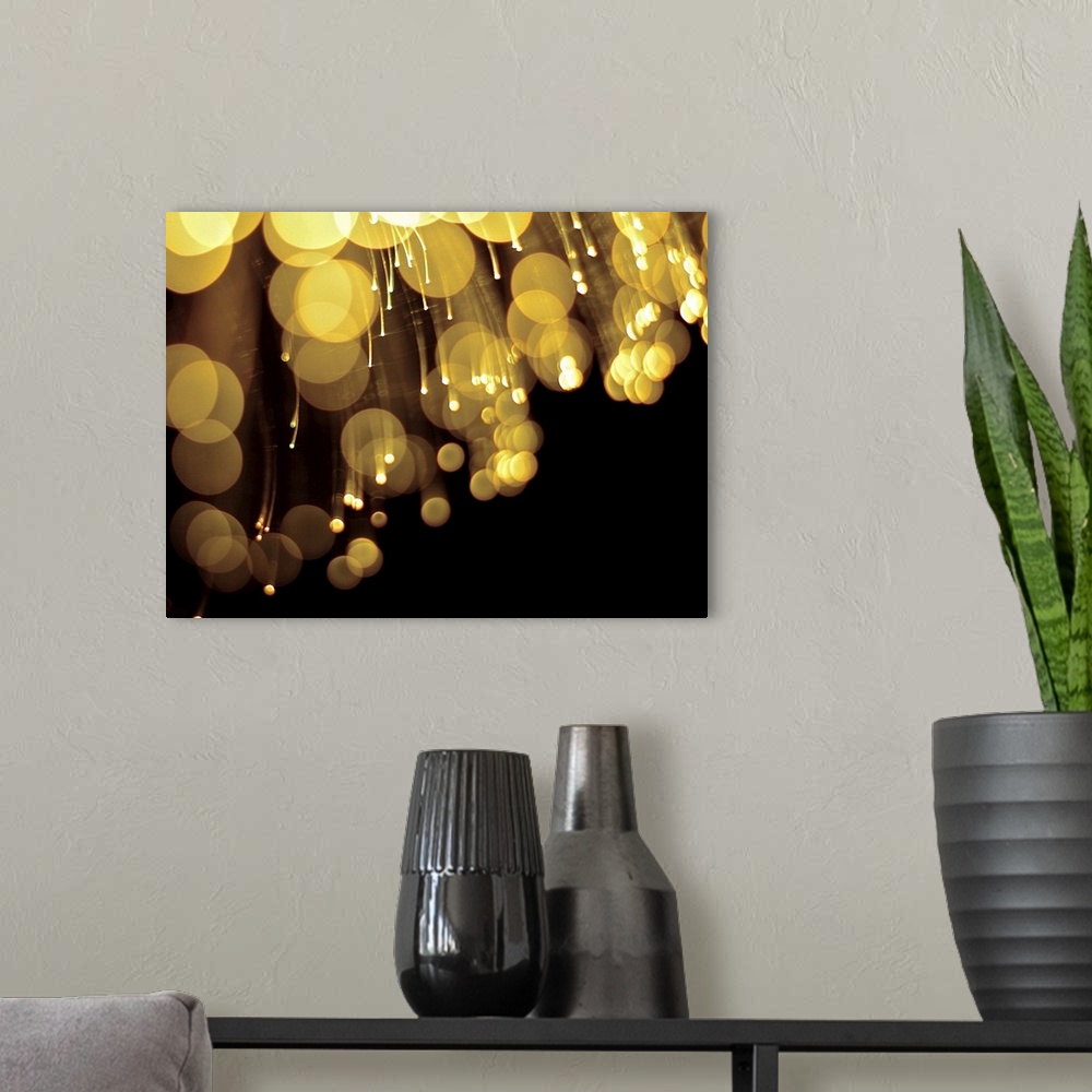 A modern room featuring Long exposure abstract photograph of gold lights with a black background.
