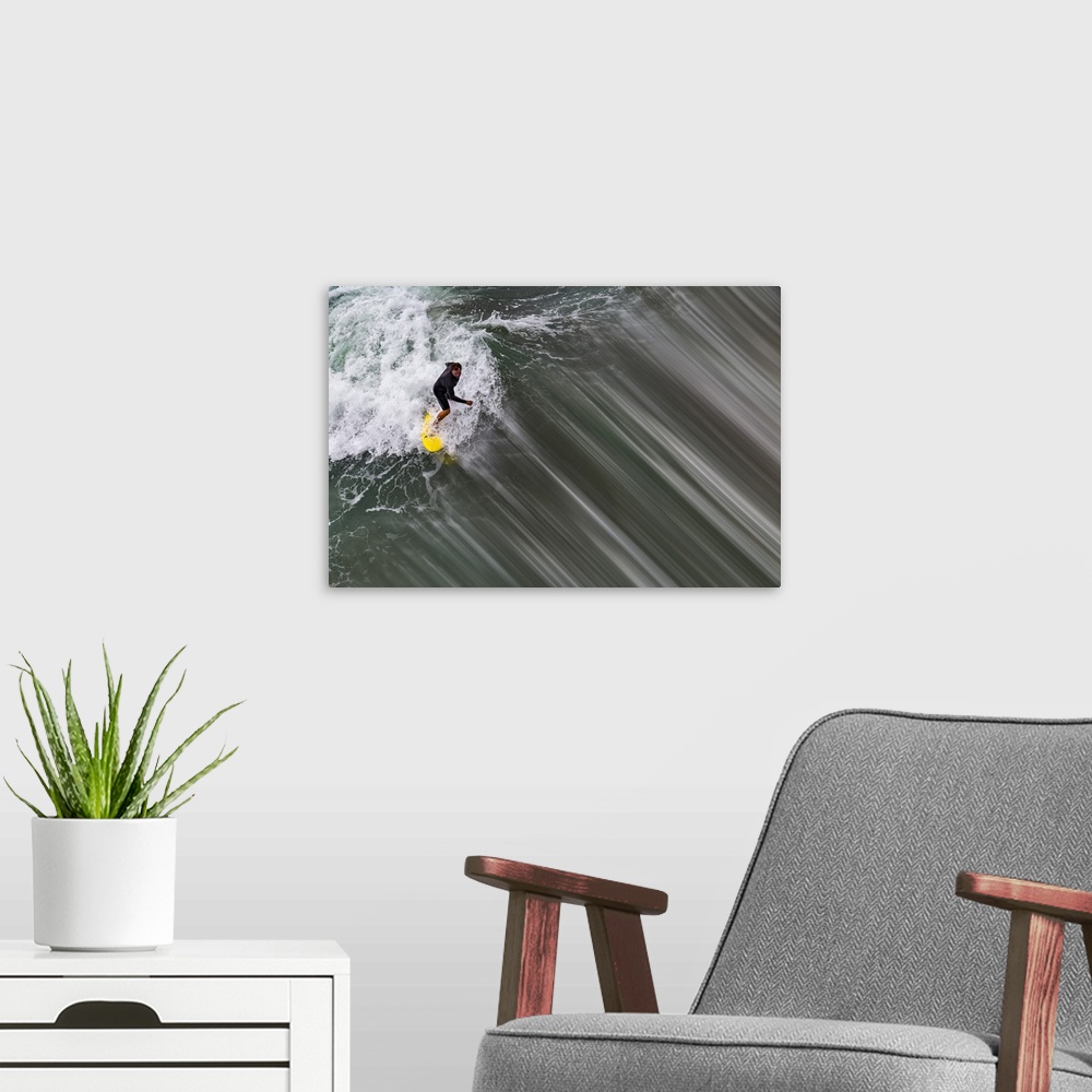 A modern room featuring Action photograph of a person surfing on a wave with a bright yellow surf board in Oceanside, Cal...
