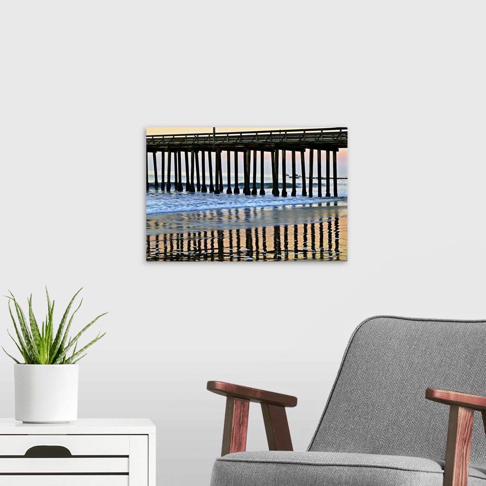 A modern room featuring Cayucos Pier silhouette and reflections onto the water at sunset.