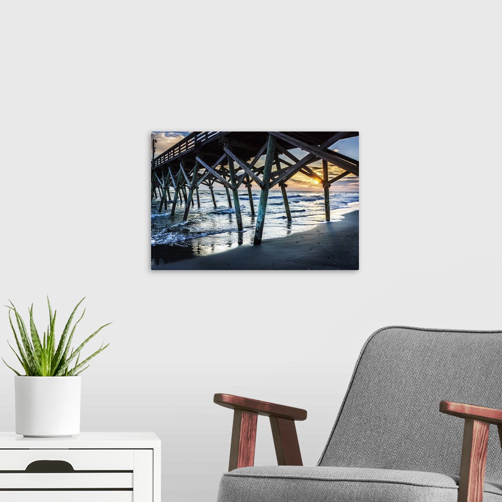A modern room featuring View of a sunrise over the ocean from underneath a wooden pier.