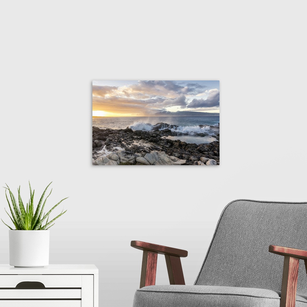 A modern room featuring Landscape photograph of a warm sunset over the ocean in Maui with waves crashing on rocks in the ...