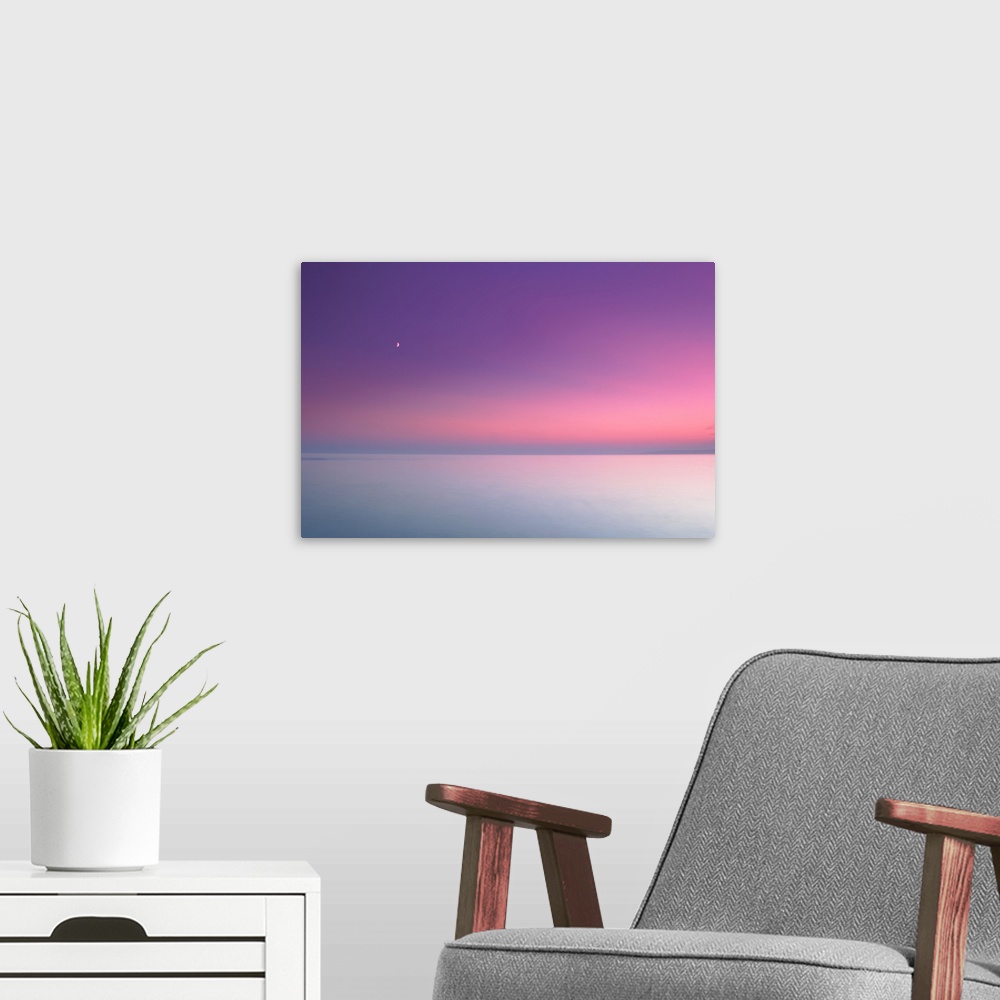 A modern room featuring After sunset on flat calm sea.
