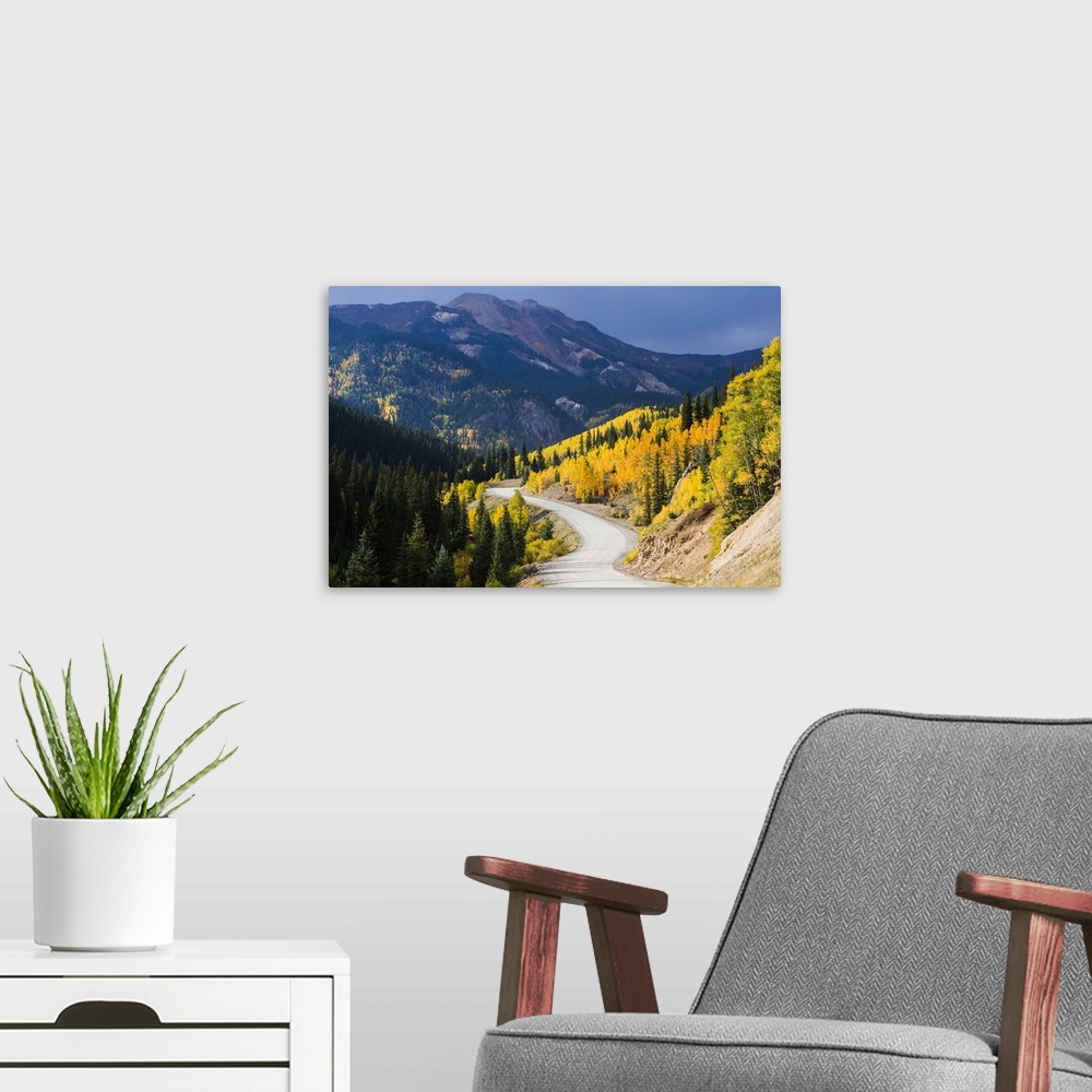 A modern room featuring A wilderness road leading to an autumn storm that is approaching mountains with brilliant fall co...