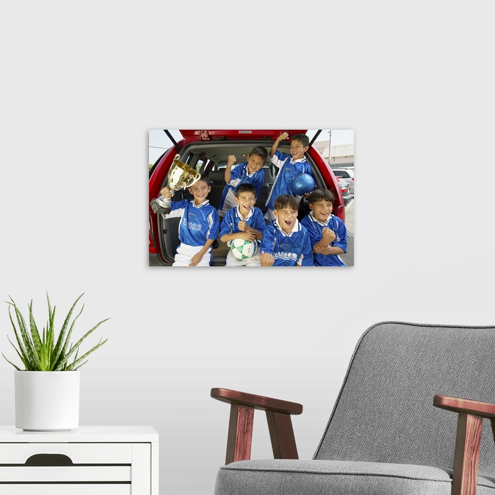 A modern room featuring Boys (7-11) football team in car boot, holding trophy, smiling