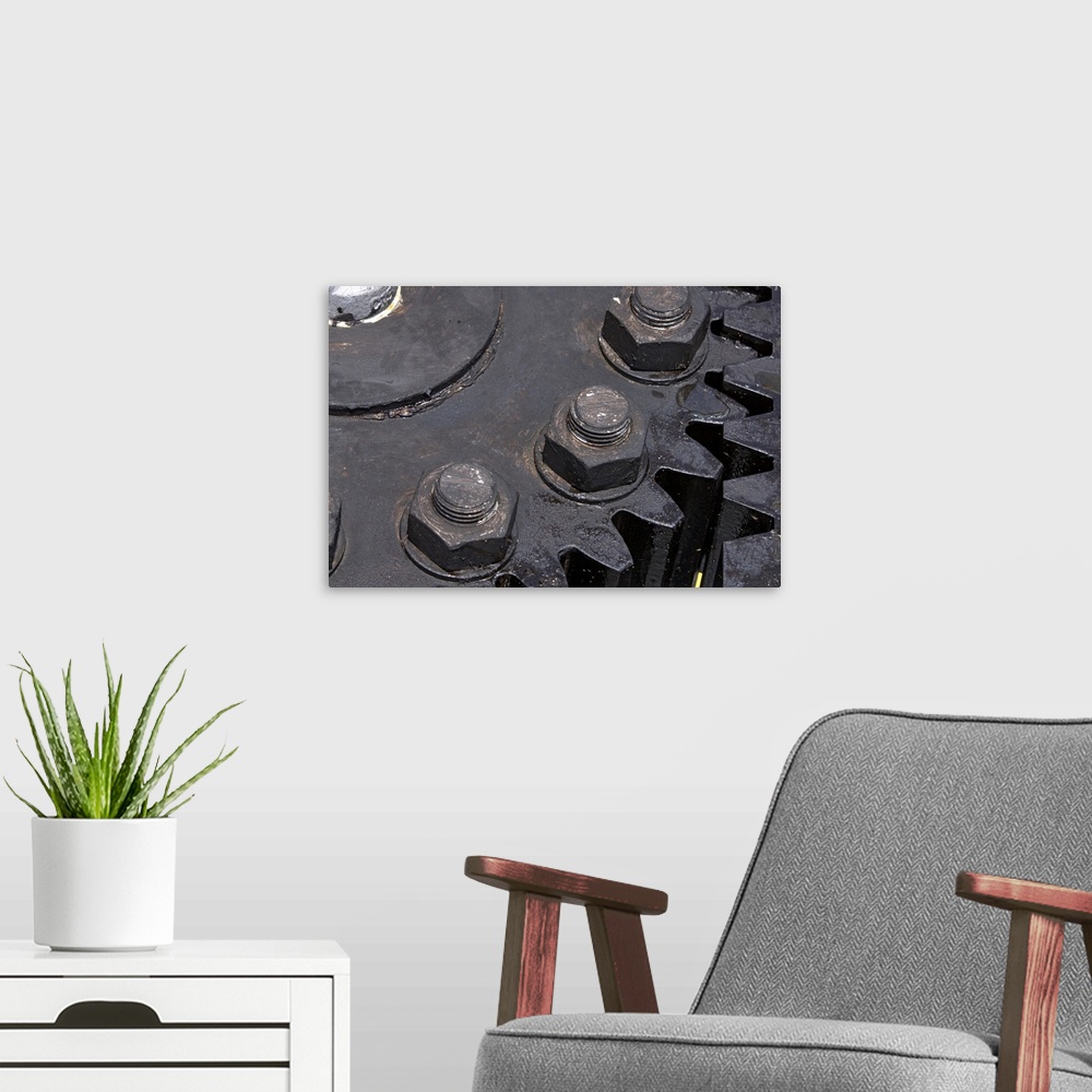 A modern room featuring Oversized, horizontal, close up photograph of the teeth meeting on two large metal gears. Large b...
