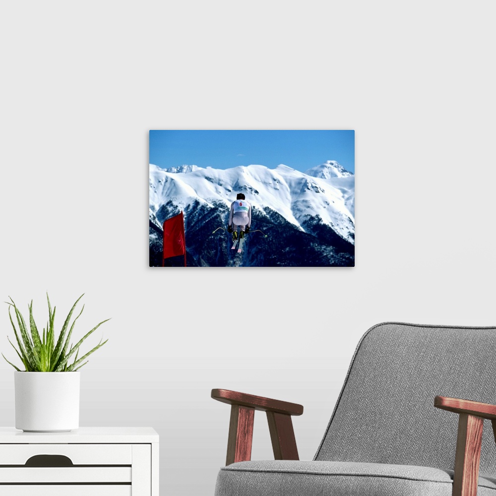 A modern room featuring Downhill skier in mid-air jump, mountains in background, rear view