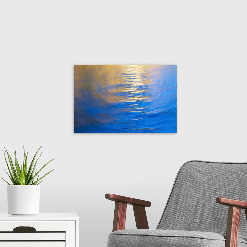 A modern room featuring Gently rippled water reflecting gold and blue colours, vortex.
