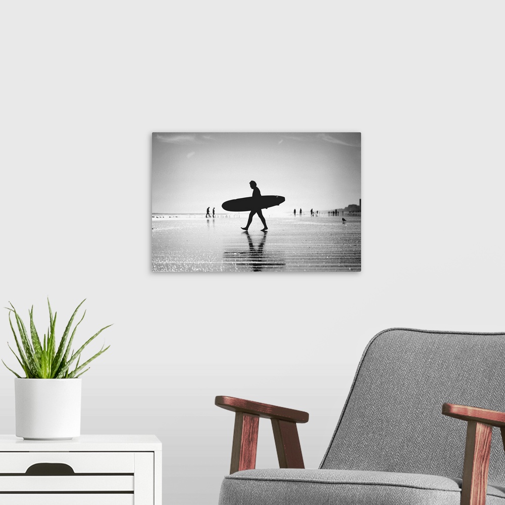 A modern room featuring Silhouette of man walking with skateboard on beach.