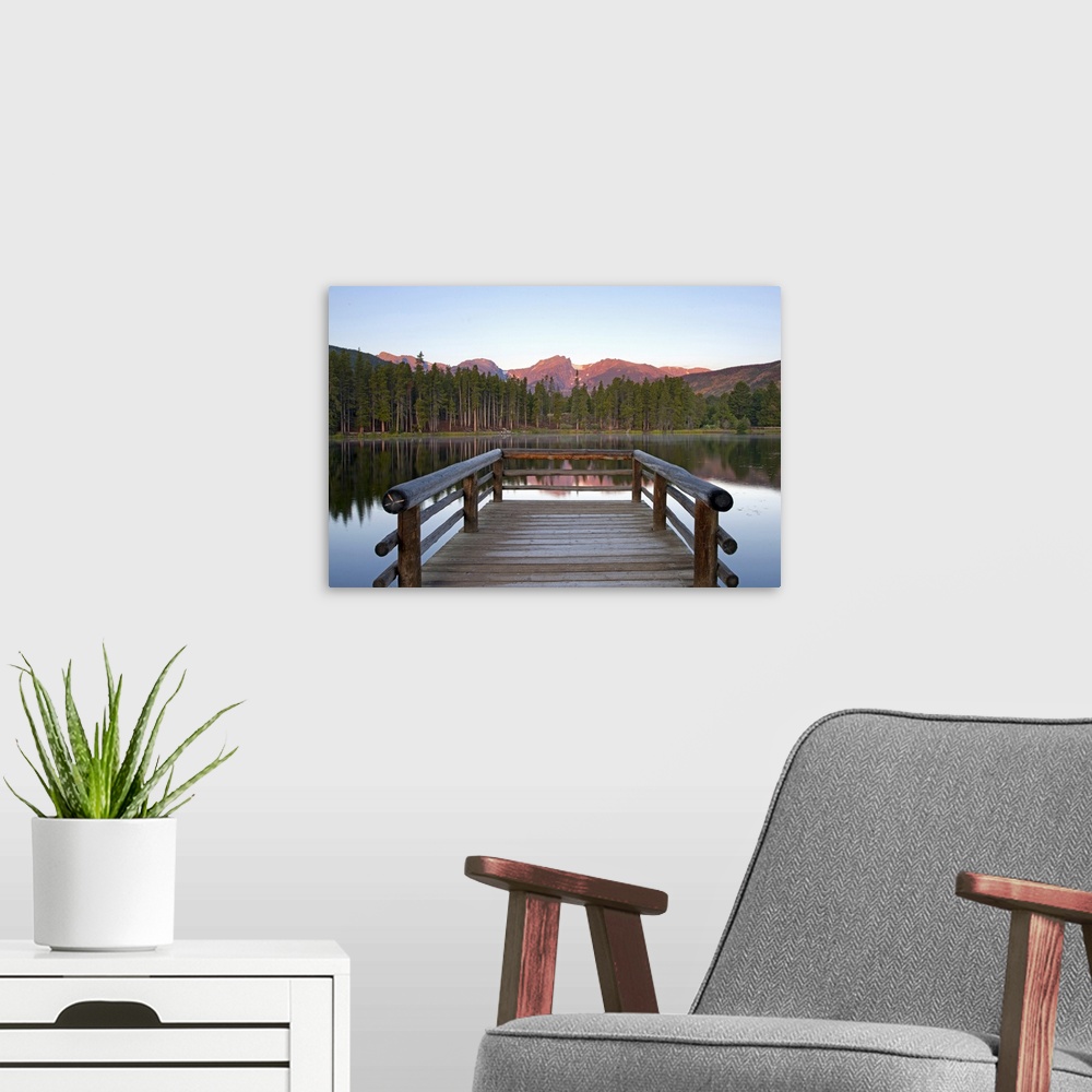 A modern room featuring A picture taken from a small dock that sits on a lake and looks out onto a mountainous view and t...