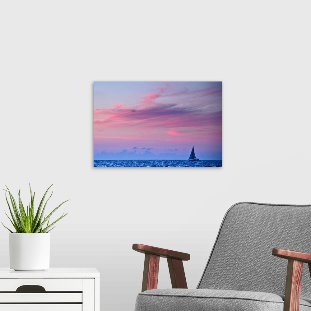 A modern room featuring Feathery clouds, colored red from the sunset, over a blue sea with a sail boat