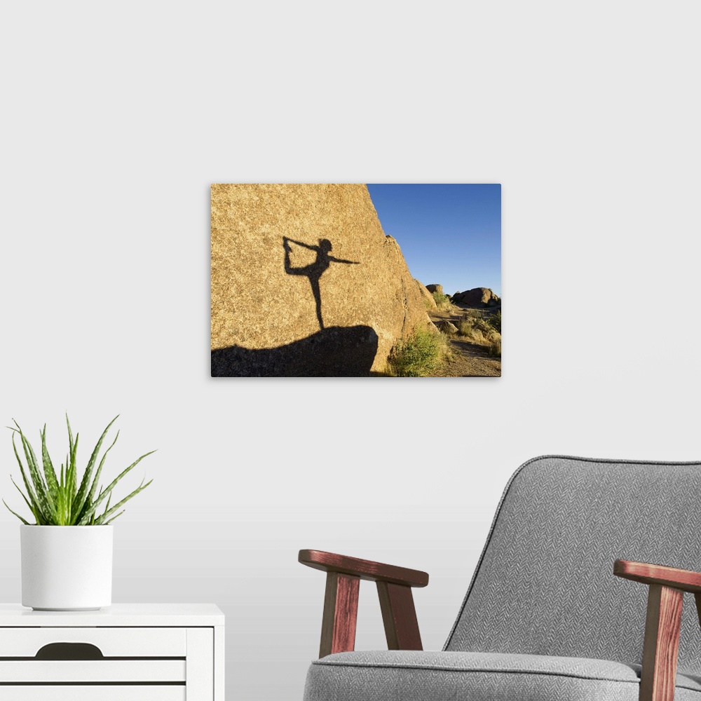 A modern room featuring Shadow of Hispanic woman practicing yoga on rock