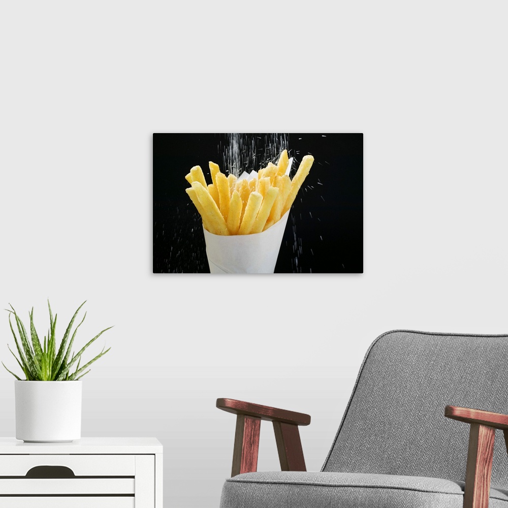 A modern room featuring Sprinkling salt on fries in paper cone