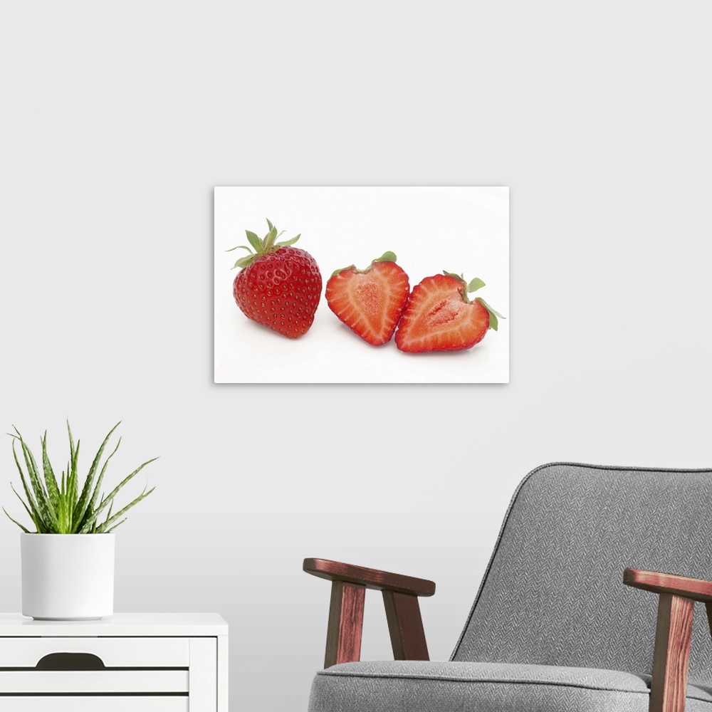 A modern room featuring Two fresh, ripe, home grown, organic strawberries, one cut into two halves, on a white background.