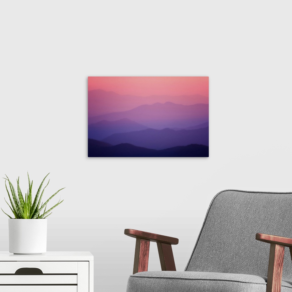 A modern room featuring Layers of the smoky mountains reach into the distance as the sky turns pink and purple in the sun...