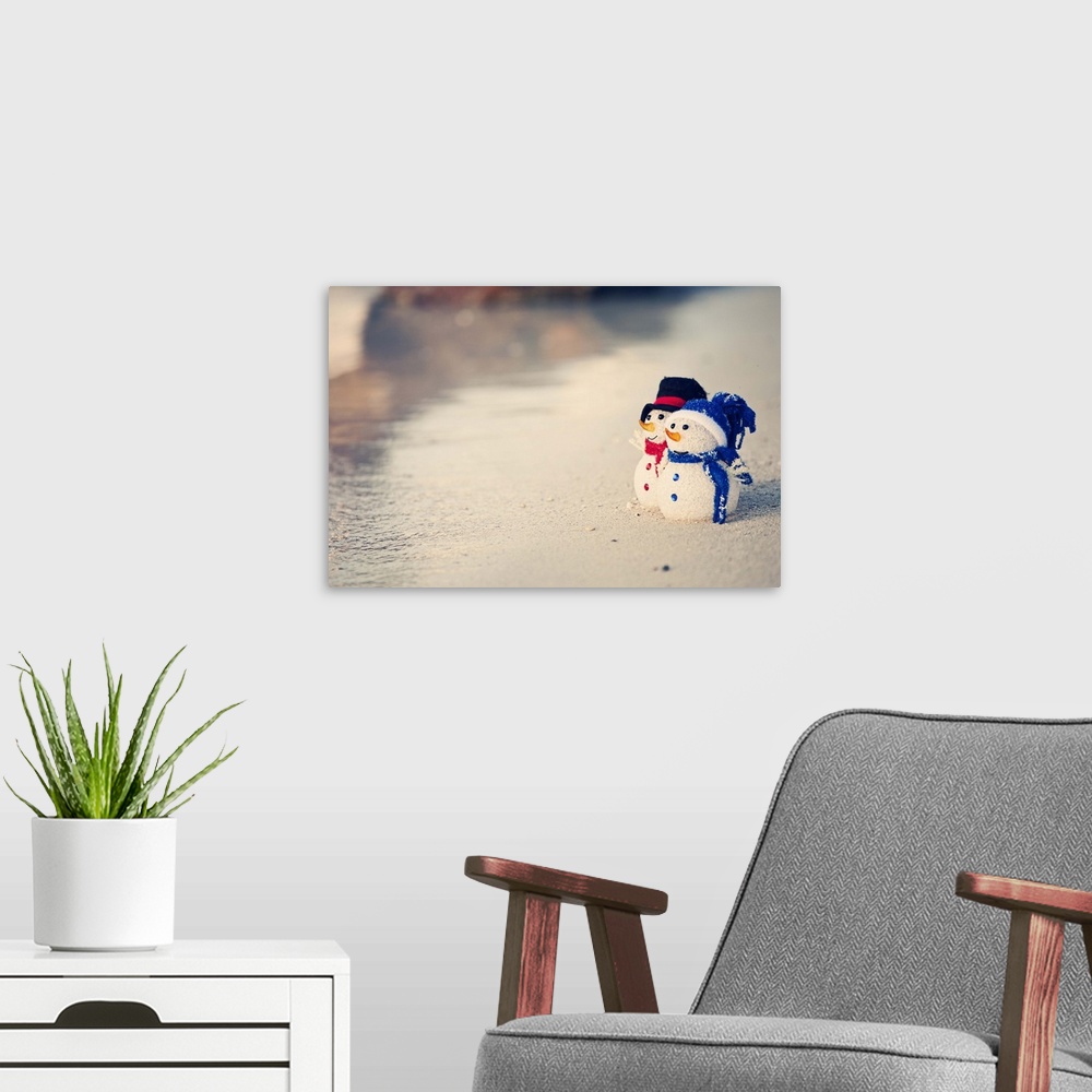 A modern room featuring Christmas time in warm weather. Waves on the white sand. Two snowman looking out to sea. Christma...