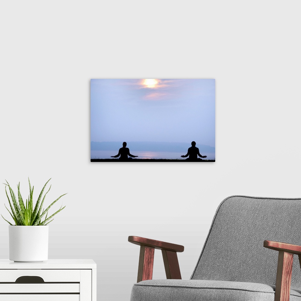 A modern room featuring Two followers of the Falun Gong spiritual practice meditate at sunrise over the Atlantic ocean.