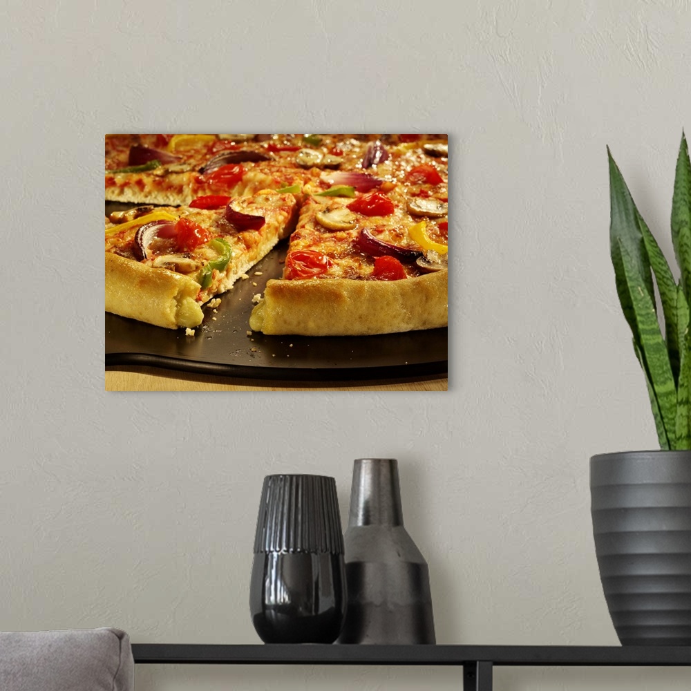A modern room featuring Vegetable pizza sliced on black pan on wood