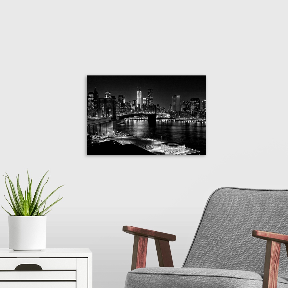 A modern room featuring Black and white photograph of a city skyline at night. With abridge spanning over bay.