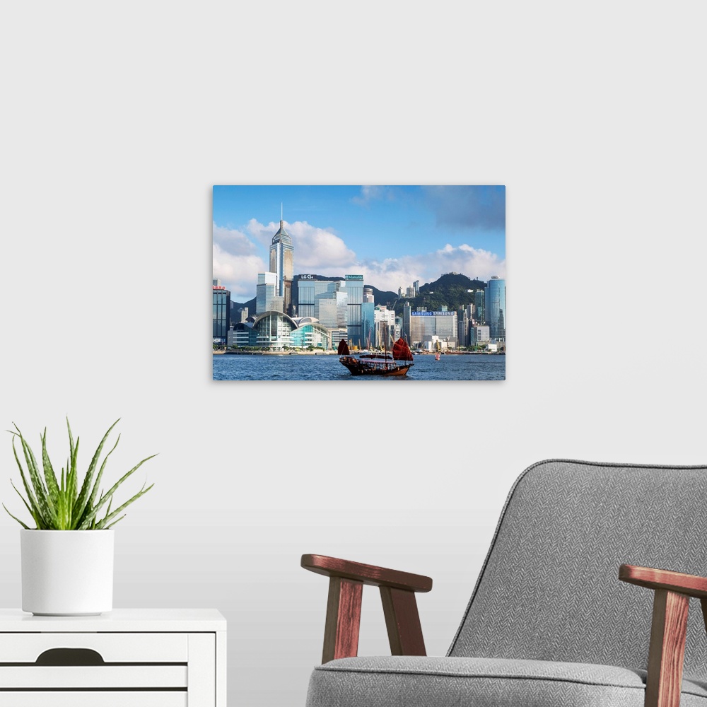 A modern room featuring Junk boat passing Convention Centre and Hong Kong Island skyline, Hong Kong, China.