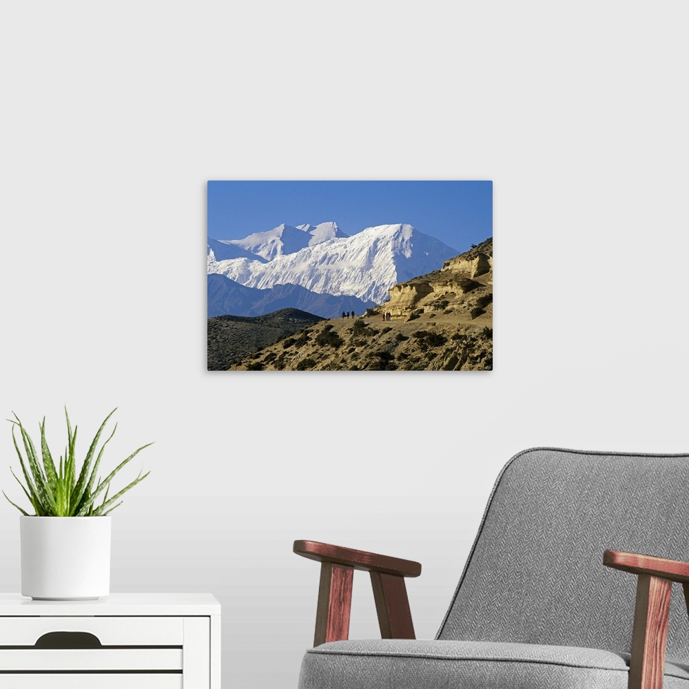 A modern room featuring Nepal, Himalaya, Mustang. Trekkers on the main Mustang trail with the Annapurna massif soaring on...