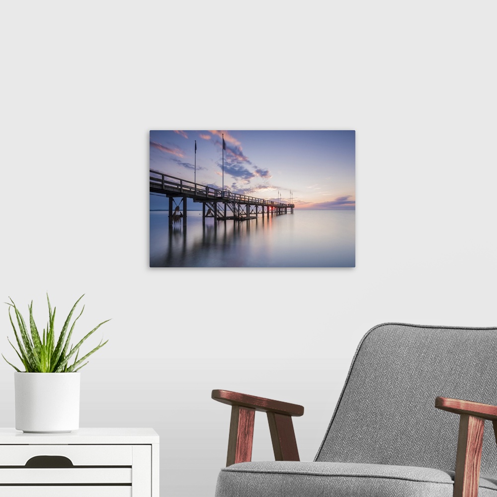 A modern room featuring Weissenhauser Strand, Ostholstein, Schleswig-Holstein, Germany. Pier over the Baltic sea at sunset.