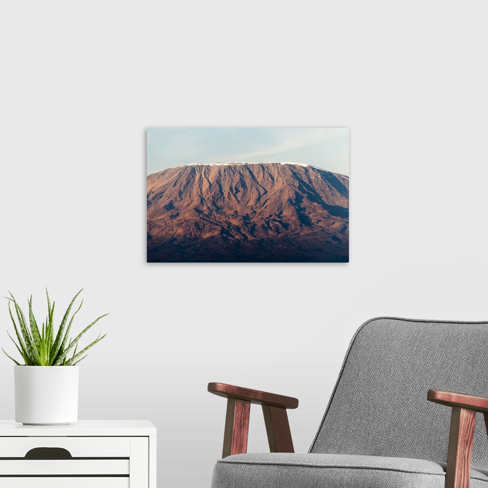 A modern room featuring Photograph of a mountain in Africa half cast in shadow from the setting sun.