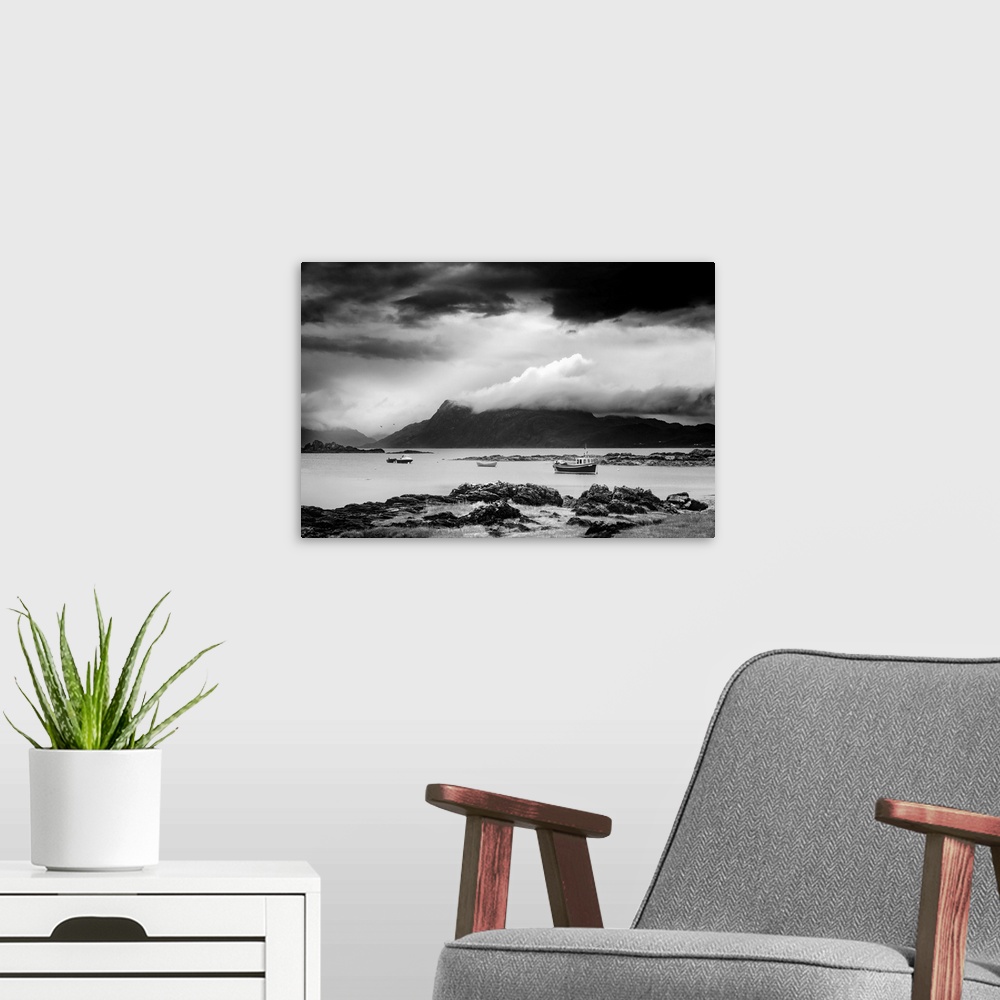A modern room featuring Black and white landscape photograph of a cloudy sky over a mountainous lake with boats.