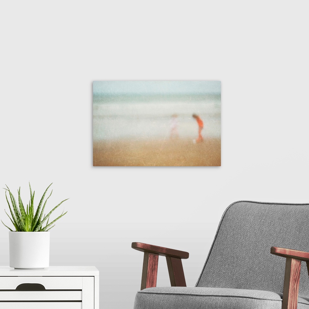 A modern room featuring Giant photograph shows two children playing on a sandy beach at the edge of an ocean.  Photograph...