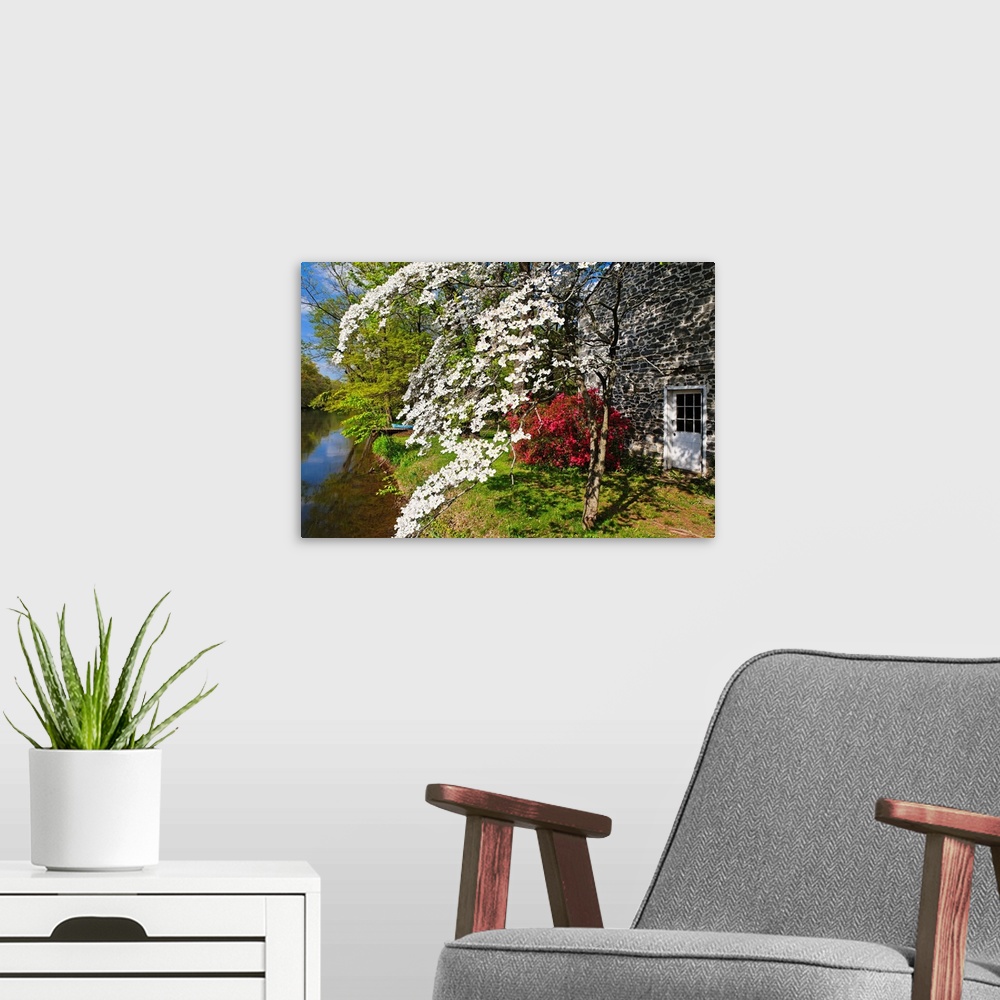 A modern room featuring Landscape photograph of spring flowers in bloom next to a stone building and at the edge of the D...