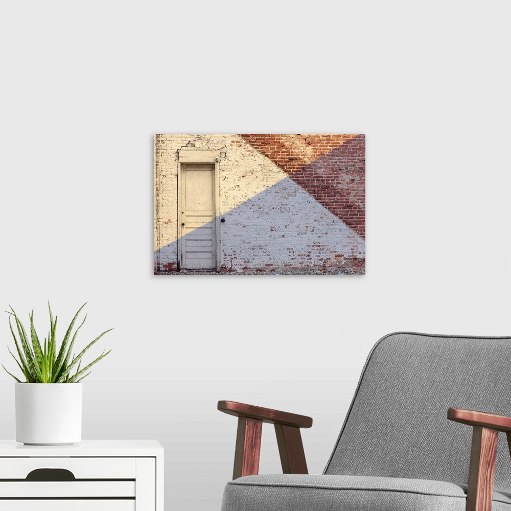 A modern room featuring Photograph of an aged brick wall with a white door, angled paint lines, and an angled shadow on h...