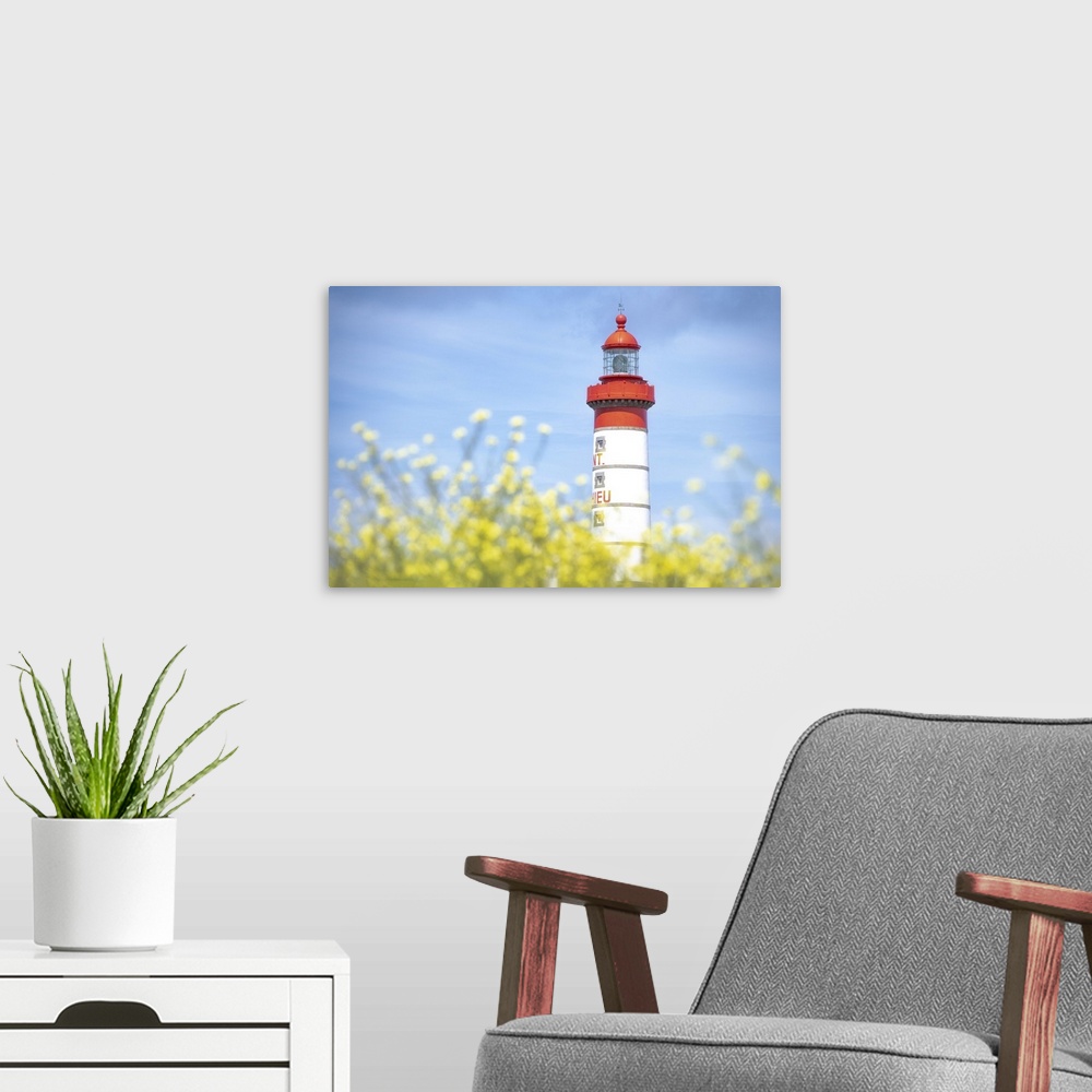 A modern room featuring Saint Mathieu lighthouse under a blue sky and behind yellow flowers in Plougonvelin, France.